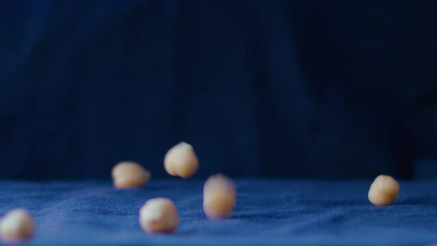 Chickpeas fall in slow motion rain, in the background and as a base there is an electric blue fabric