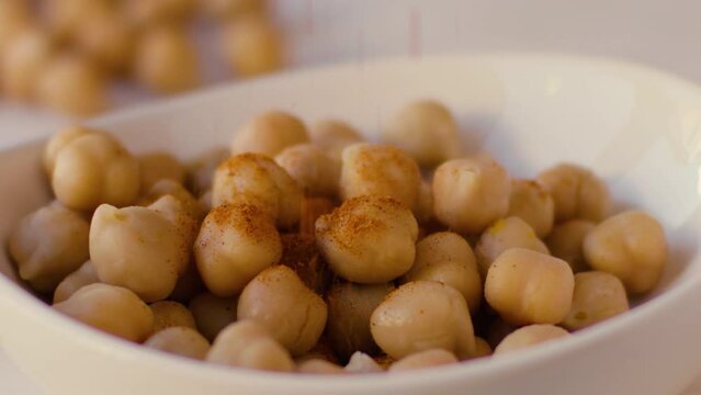 Curry rain falls in slow motion on chickpeas placed in a white bowl