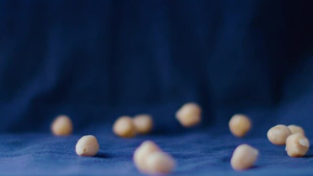 A rain of chickpeas falls in slow motion against an electric blue background