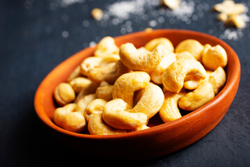 cashew nuts in bowl on dark table, top view