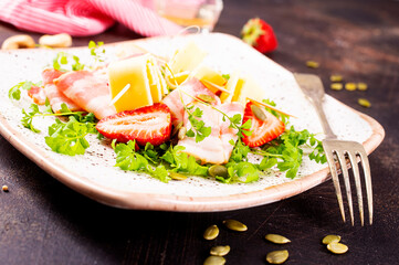 Salad with cheese, bacon, greens and strawberries