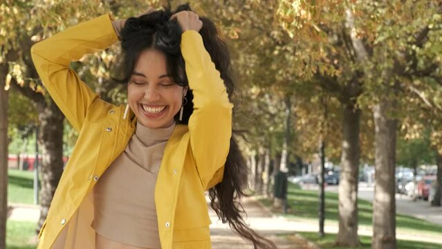 Young latin girl dancing bachata dressed in yellow raincoat at street in autumn.