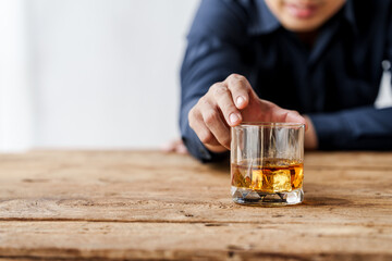 Sad depressed addicted drunk guy, Alone asian man drinker alcoholic sitting at bar counter with glass drinking whiskey.