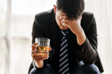 Sad depressed addicted drunk guy, Alone asian man drinker alcoholic sitting at bar counter with glass drinking whiskey.