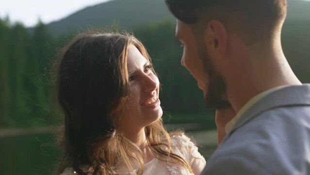 loving newlyweds on the shore of a mountain lake. Steadycam shot with sun glare.