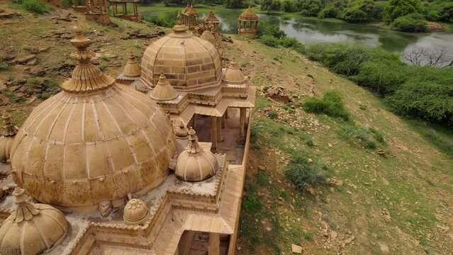 Hillside Bada Bagh Temple Domes In Jaisalmer Beside Lake. Aerial Flying Low. Dolly Forward 
