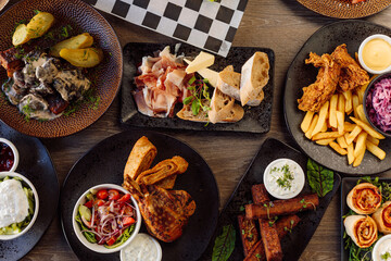 Appetizer, main course, dessert on cafe table. Cheese, meat plate, vegetables, pepper with roast chicken, french fries