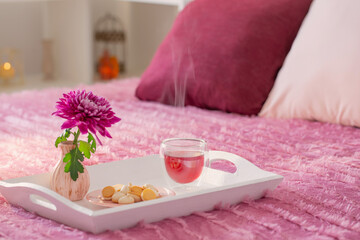 Obraz na płótnie Canvas red tea in thermo glass with flowers in modern bedroom