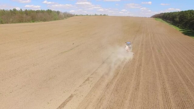 Tractor spreading artificial fertilizers in field. Top view, aerial shooting