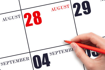 A hand holding a red pen and pointing on the calendar date August 28. Red calendar date, copy...