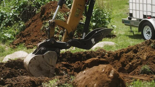 Excavator digging with water tanks and trailer in background (4k 30p Slow Motion)