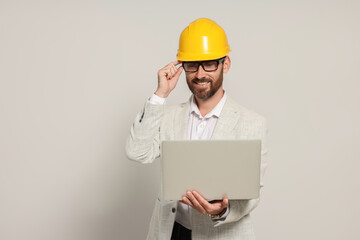 Professional engineer in hard hat with laptop on white background