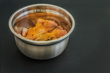 pieces of fresh raw chicken fillet marinated with spices in a metal bowl