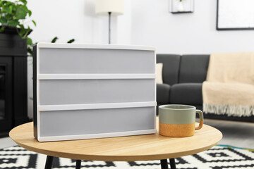 Blank letter board and cup of drink on wooden table indoors