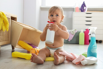 Cute baby playing with bottle of detergent on floor at home. Dangerous situation