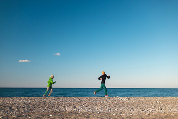 A child with his mother runs along the beach