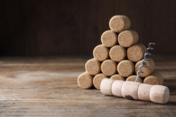 Corkscrew and wine corks on wooden table. Space for text