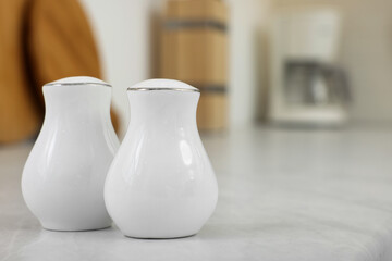 Fototapeta na wymiar Ceramic salt and pepper shakers on white table in kitchen. Space for text