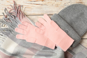 Stylish pink woolen gloves, scarf and hat on white wooden table, flat lay