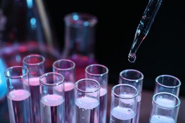 Dripping reagent into test tube on black background, closeup. Laboratory analysis