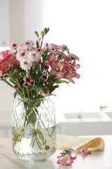 Vase with beautiful flowers on table in kitchen. Stylish element of interior design