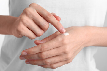 Woman applying cream onto hand, closeup view
