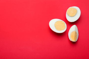 Cut fresh hard boiled eggs on red background, flat lay. Space for text