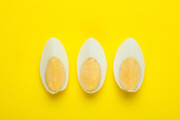 Slices of fresh hard boiled egg on yellow background, flat lay