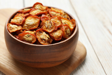Bowl with cut dried kumquat fruits on white wooden table, closeup