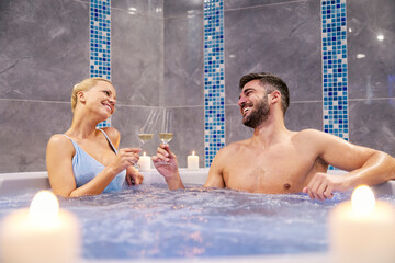 A romantic couple drinks champagne in the hot tub.
