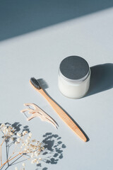 Packaging for cleaning teeth without plastic. Wooden toothbrush, thread and glass jar with toothpaste on a grey background. Dental hygiene zero waste. Bathroom accessories, oral care