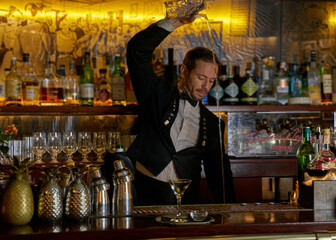 Bartender preparing a cocktail inside a metal pineapple on an authentic wooden bar . 