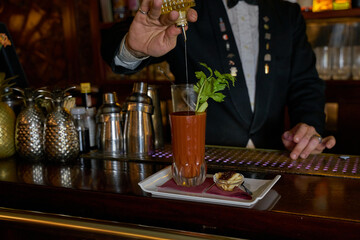 Bartender preparing a bloody mary on an authentic wooden bar counter. 