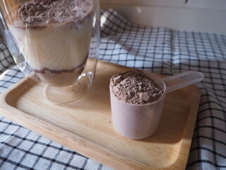 Lifestyle healthy concept: Whey protein chocolate flavor scoop on wooden tray. Plant-based protein are good choice for health.