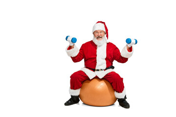Portrait of senior man in image of Santa Claus sitting on exercise ball and doing exercises with...