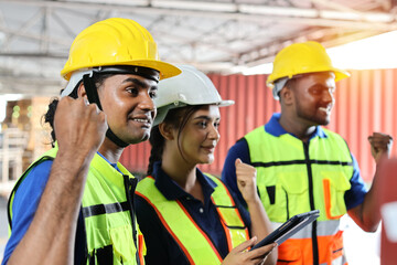 Group of warehouse workers with hardhats and reflective jackets standing and raising hands celebrate successful together or completed deal commitment at retail warehouse logistics, distribution center