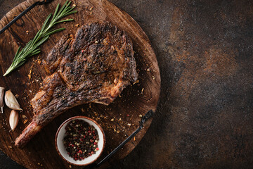 Dry-aged marble beef steak Tomahawk on wooden board with spices. Flat lay, dinner concept