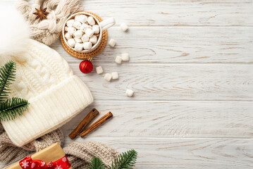 Winter holidays concept. Top view photo of headwear cozy plaid red bauble pine branches cup of hot drinking with marshmallow stylish giftbox anise and cinnamon sticks on white wooden table background