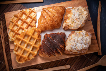 Waffle and Croissants in wooden plate on wooden table, Freshly baked croissants and Waffle on brown wooden table.