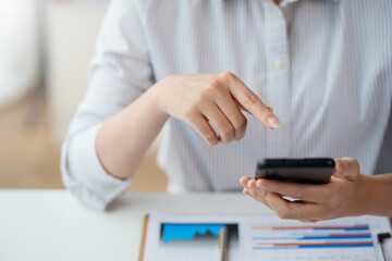 Fototapeta premium Close-up of a woman using a smartphone to work on various social media applications. including mobile transactions and LINE messaging and other business information via LINE.