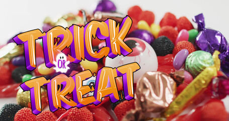 Image of halloween trick or treat text over sweets on grey background