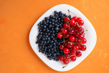 berries of ripe cherries and blueberries on a plate, summer seasonal berries