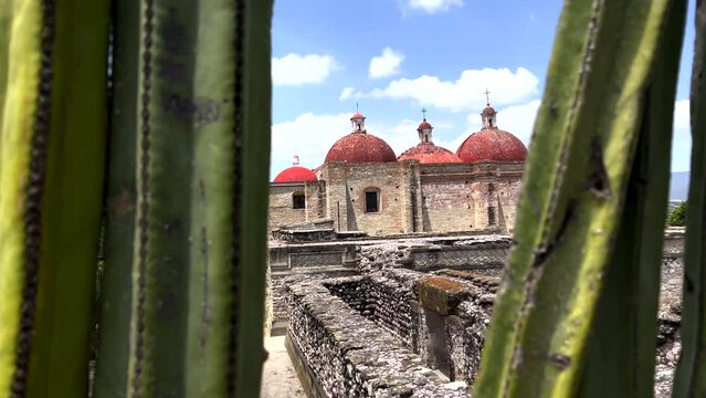 Ancient Ruins Site of Mitla Oaxaca Mexico, Close Up Dolly View Through Cactus Plant of Stone Ruins Walls and Old Architectural Church Religious Monument in Background, Archeological Tourist Site