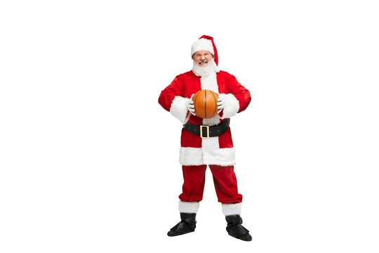 Portrait of senior man in image of Santa Claus posing with basketball ball isolated over white background. Competition