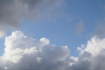 White, fluffy clouds in blue sky. Background from cumulus clouds. Scenery above the clouds