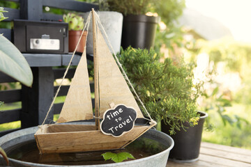 Time to travel concept! Big journeys begin with small steps! Toy sailboat in a water bowl