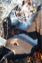 A hole in the knitted fabric. Burning old clothes after an infectious disease