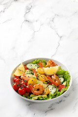 Fresh seafood salad with shrimps, prawns, avocado, cucumber on white marble background. Copy space. Shrimps salad. Healthy diet concept.