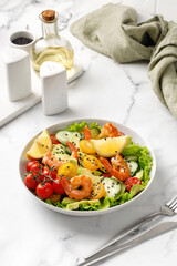 Fresh seafood salad with shrimps, prawns, avocado, cucumber on white marble background. Shrimps salad with vegetables. Healthy diet concept.