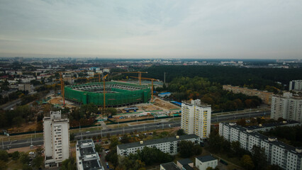 Building a stadium in a big city. Construction site among urban areas. Aerial photography.